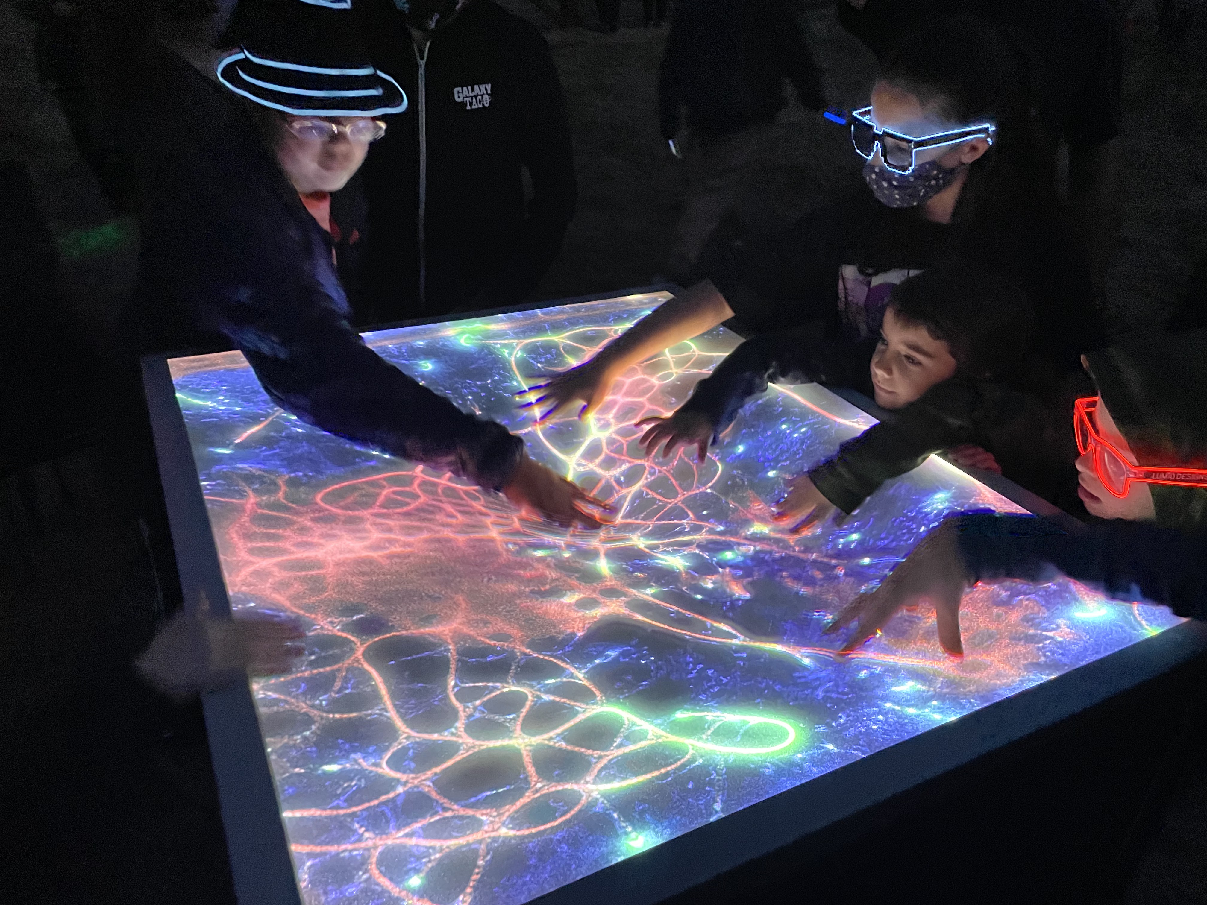 Visitors interacting with Nocturna's projected generative tide pool
